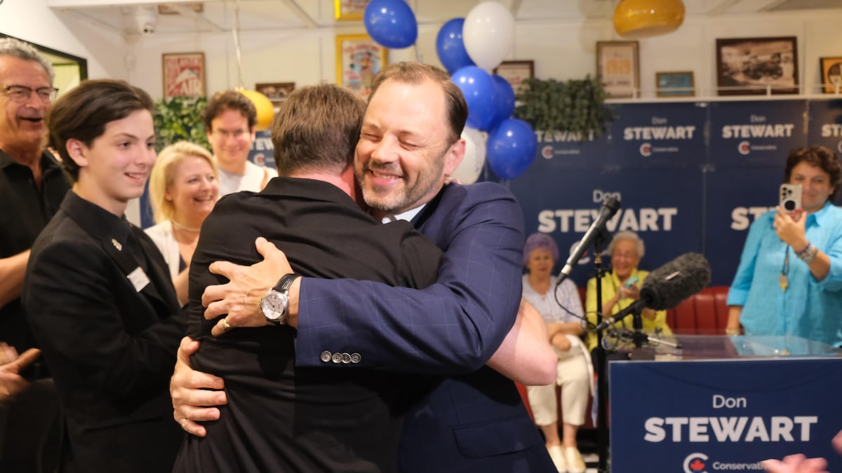 Don Stewart, souriant, serre un homme dans ses bras lors d'un rassemblement de campagne.
