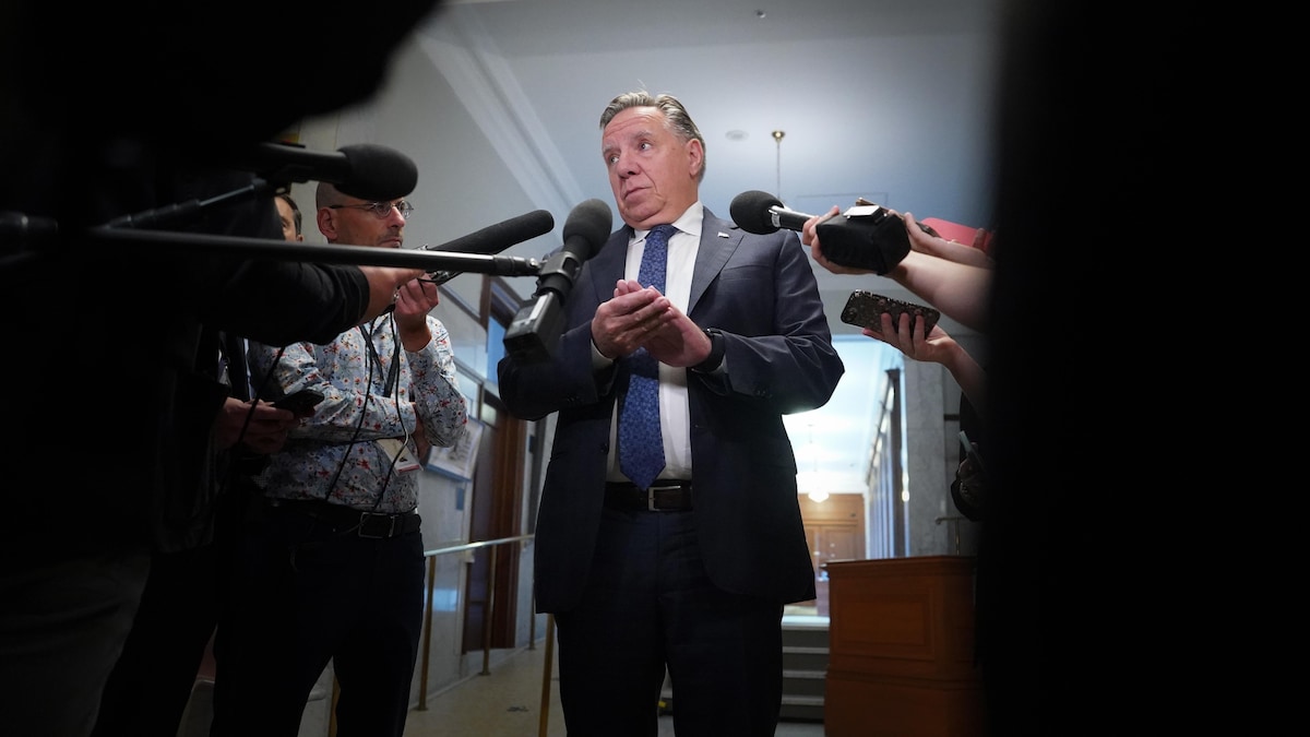 François Legault, entouré de micros, s'adresse à des journalistes.