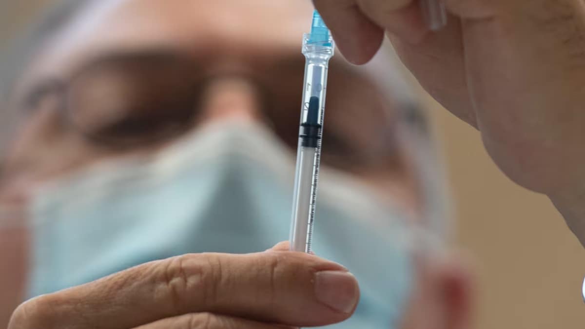 Un médecin manipule une seringue contenant une dose de vaccin.