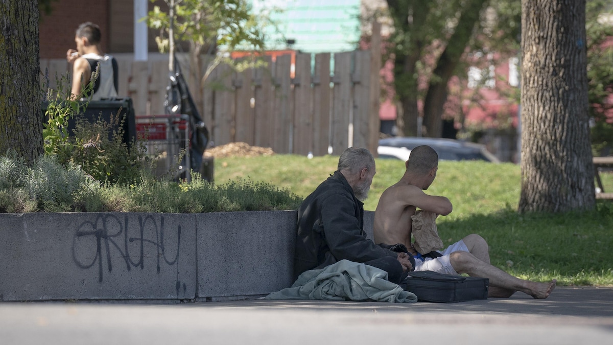 Deux hommes qui semblent démunis, assis par terre.