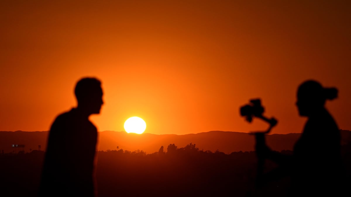 Deux personnes marchent à l'extérieur avec, en toile de fond, un coucher de soleil en Californie, aux États-Unis.