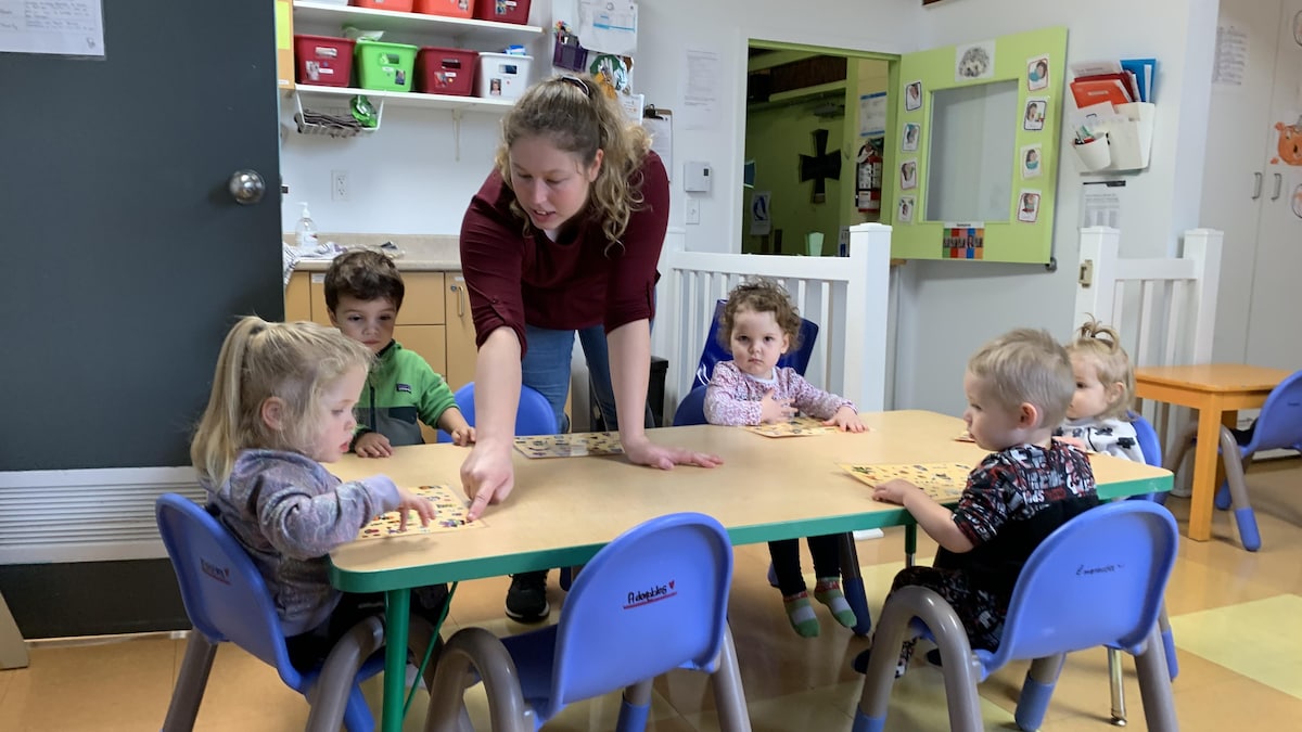 Kim Sorel avec de jeunes enfants, assis à une table, en train de faire un jeu éducatif.