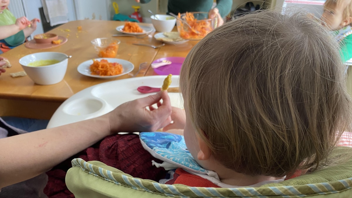 Un bambin à l'heure du dîner, assis à table.