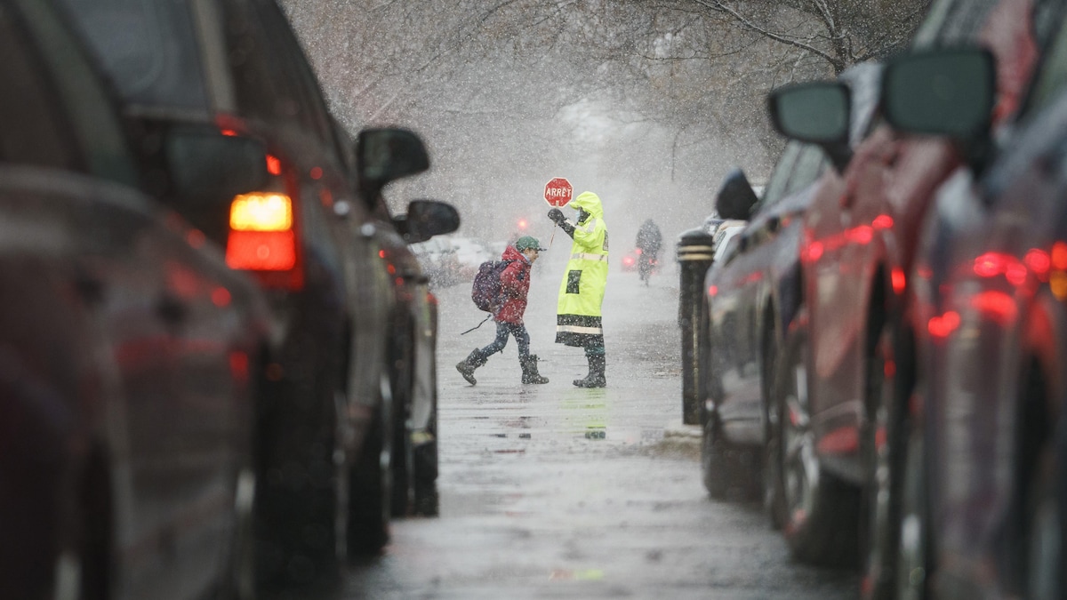 Un enfant traverse une rue tout près d'un brigadier.