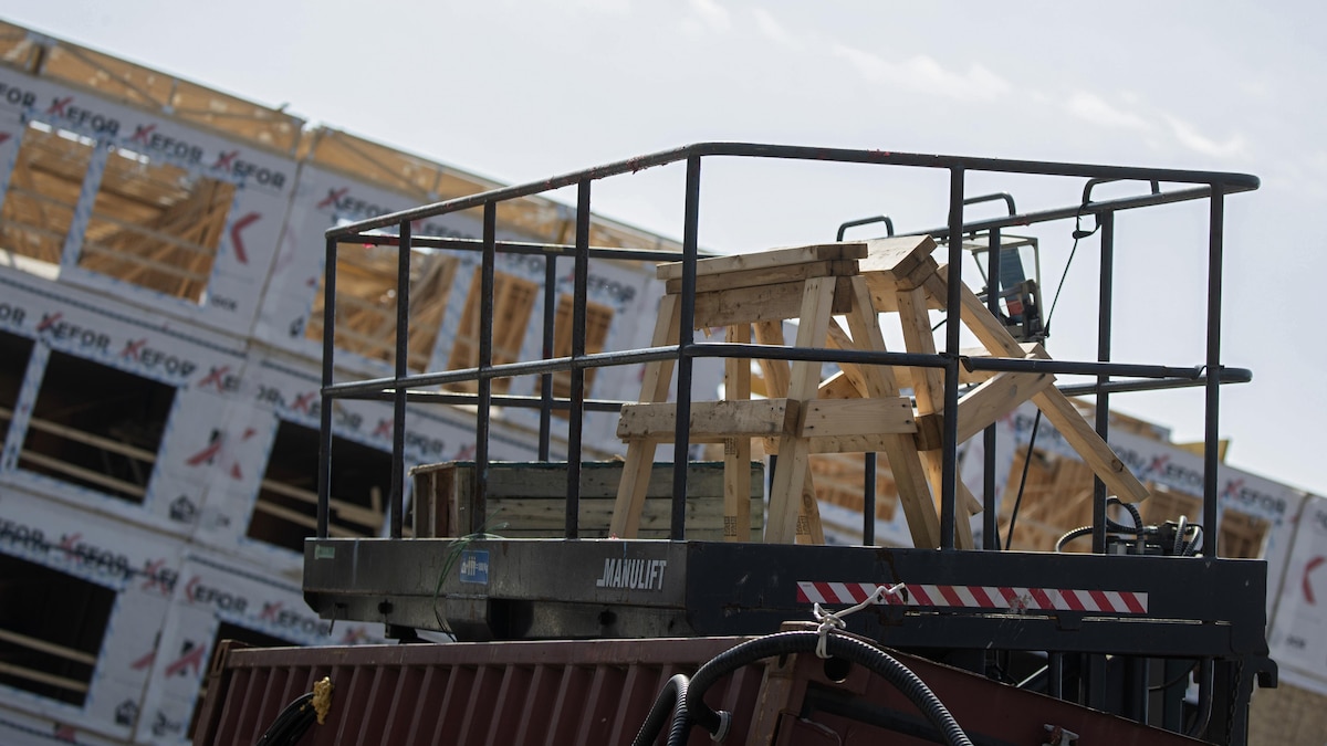 Un monte-charge qui contient du matériel se trouve devant un immeuble en construction.