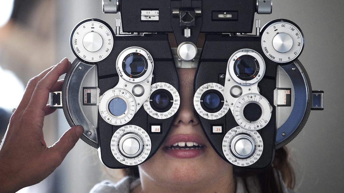 Vue de face d'une jeune personne effectuant un examen de la vue dans une clinique.