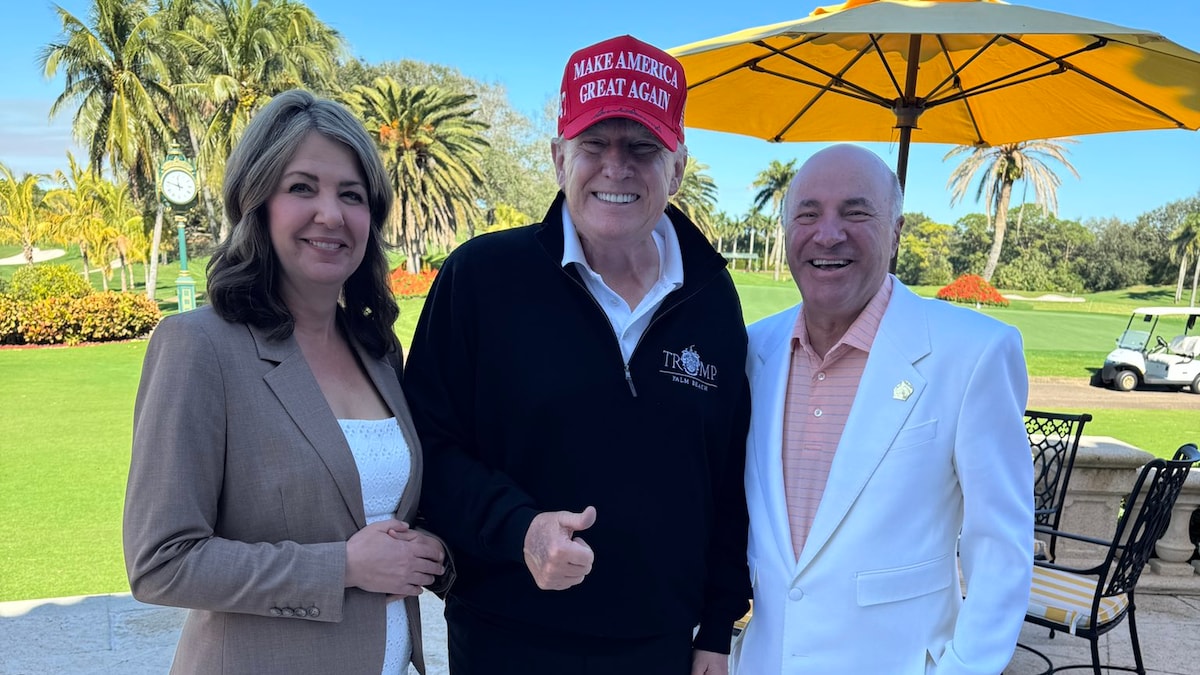 Trois personnes sourient devant un parasol.