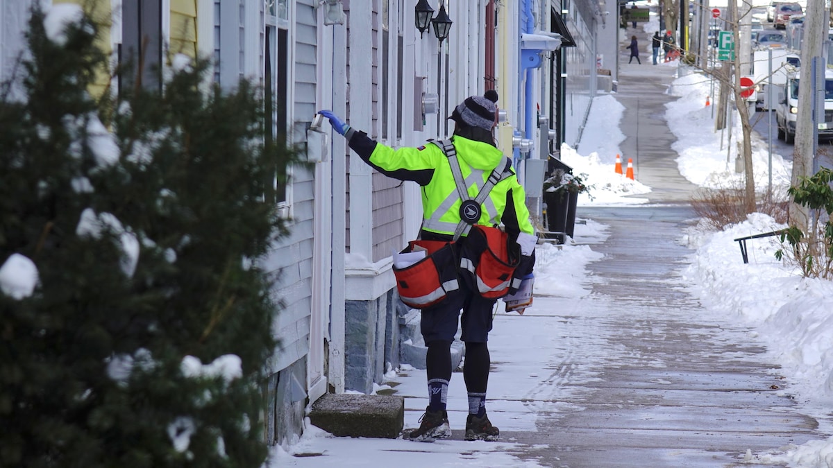 Un postier de Poste Canada livre le courrier dans une rue d'Halifax, en Nouvelle-Écosse.